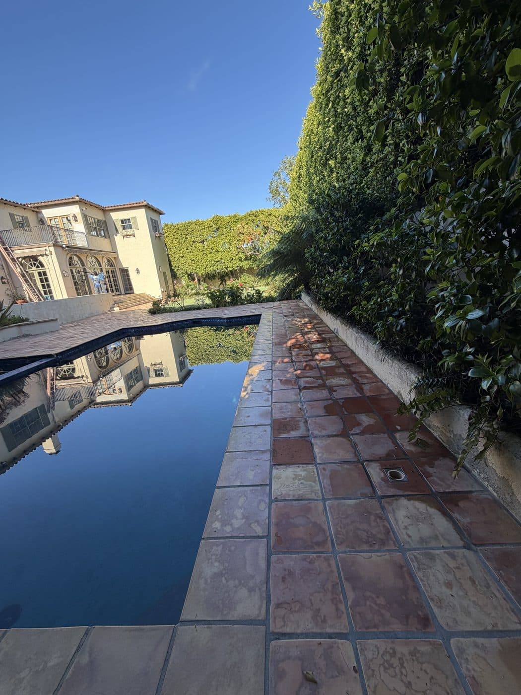 A saltillo tile pool deck beside a clean reflecting pool, cleaned by Window Wizards